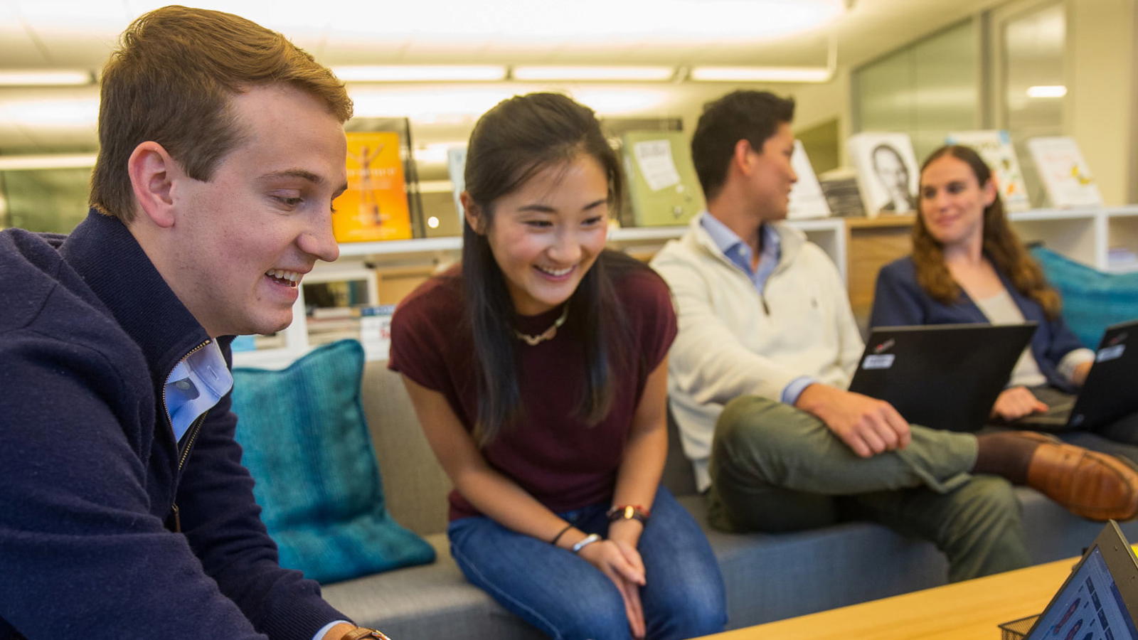 a group of people sitting on couches looking at a laptop